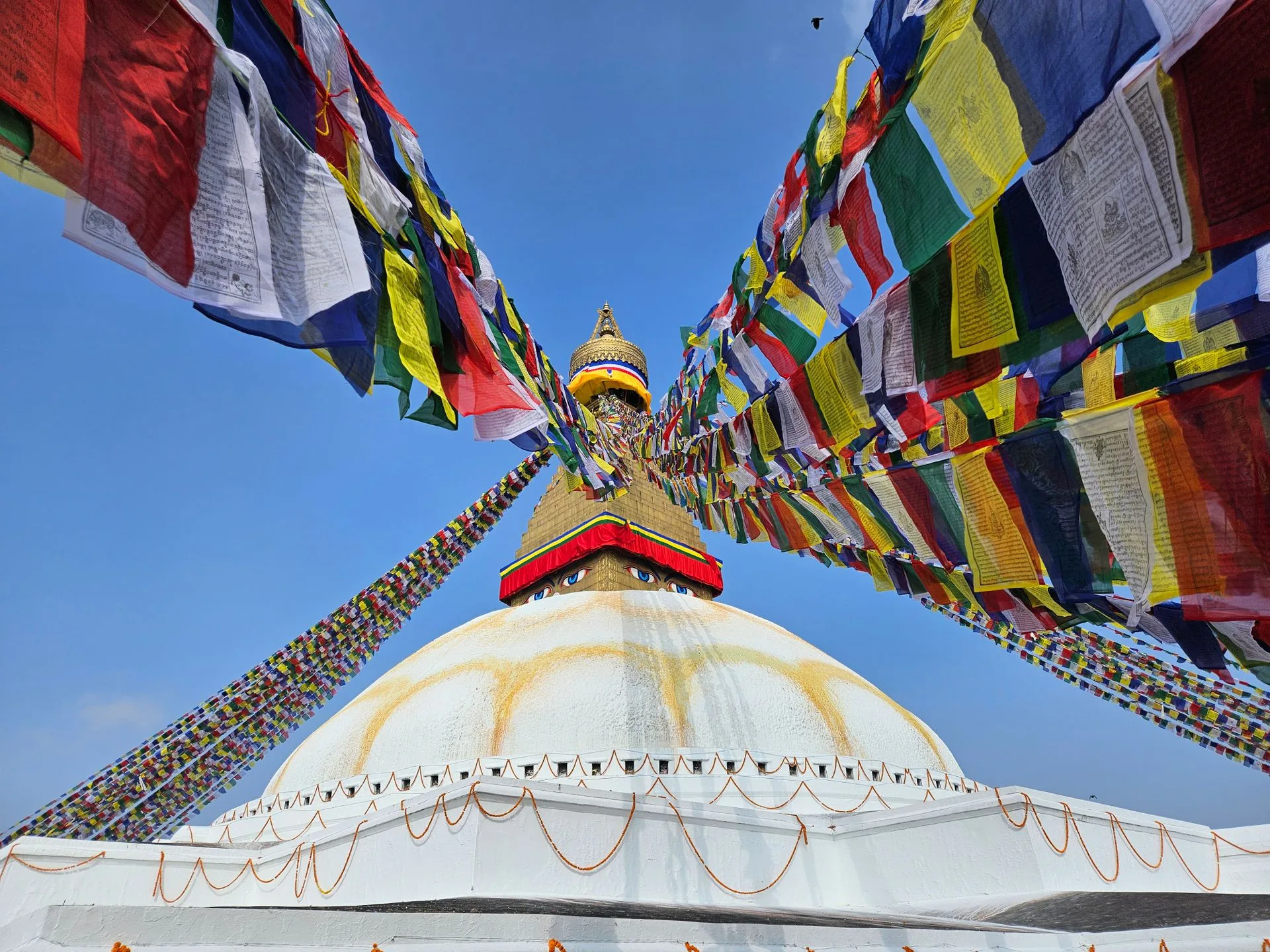Boudhanath Stupa with prayer flags and pilgrims during golden hour