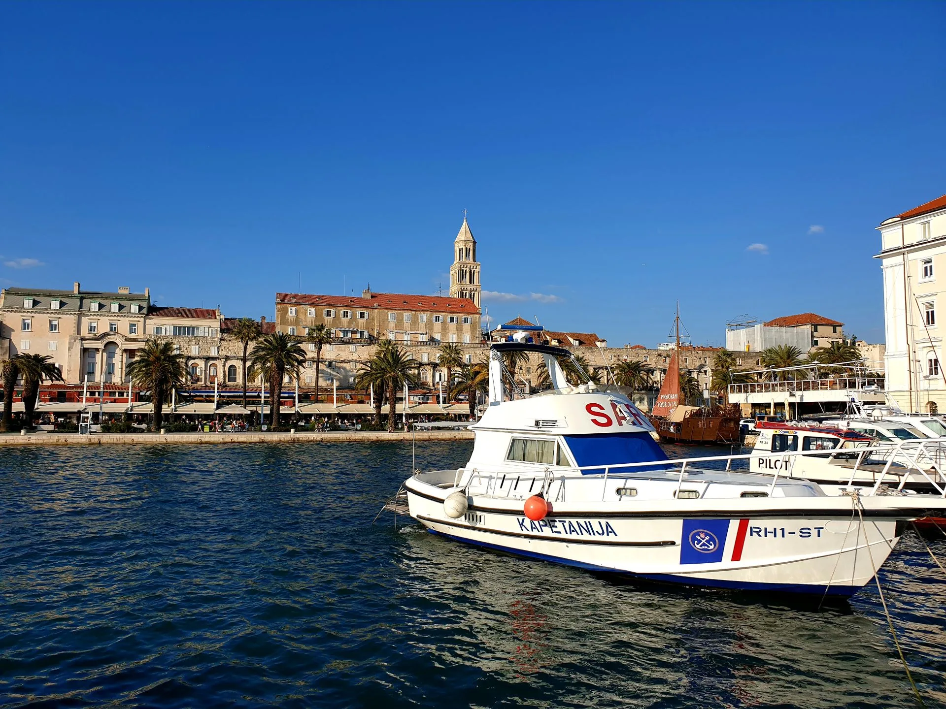 Trogir waterfront with palm trees, boats, and historic cathedral