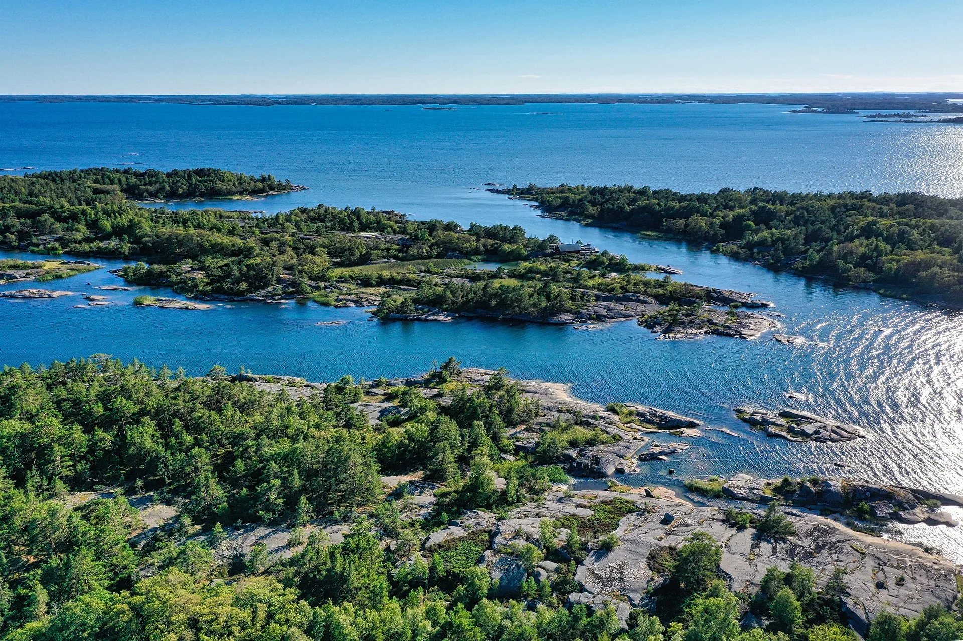 Red cottage on rocky island in Stockholm Archipelago surrounded by calm waters