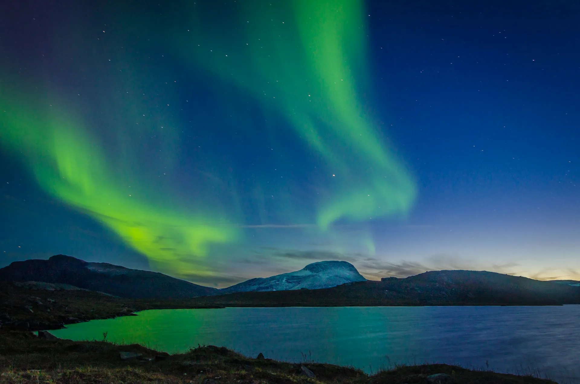 Northern Lights Aurora Borealis dancing over snow-covered landscape in Abisko