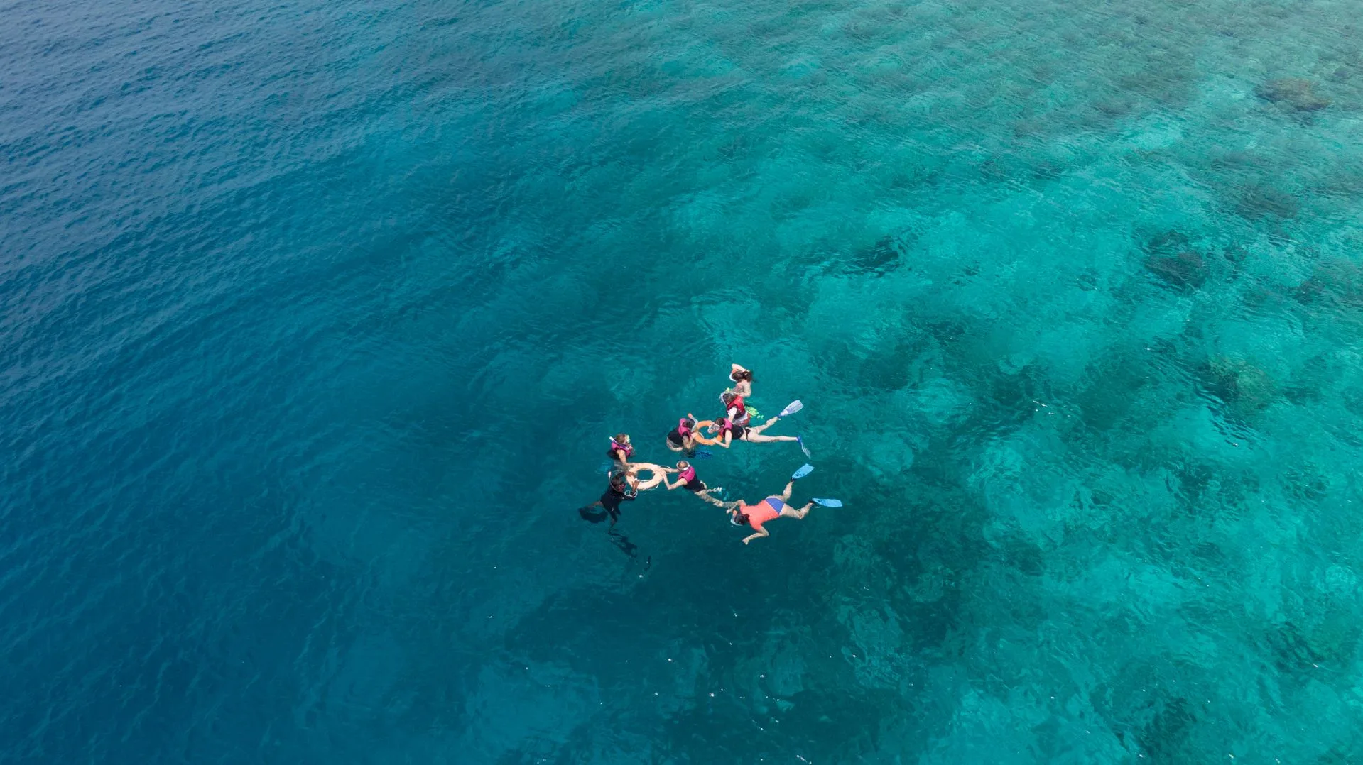 Family snorkeling in crystal clear turquoise waters with coral reef