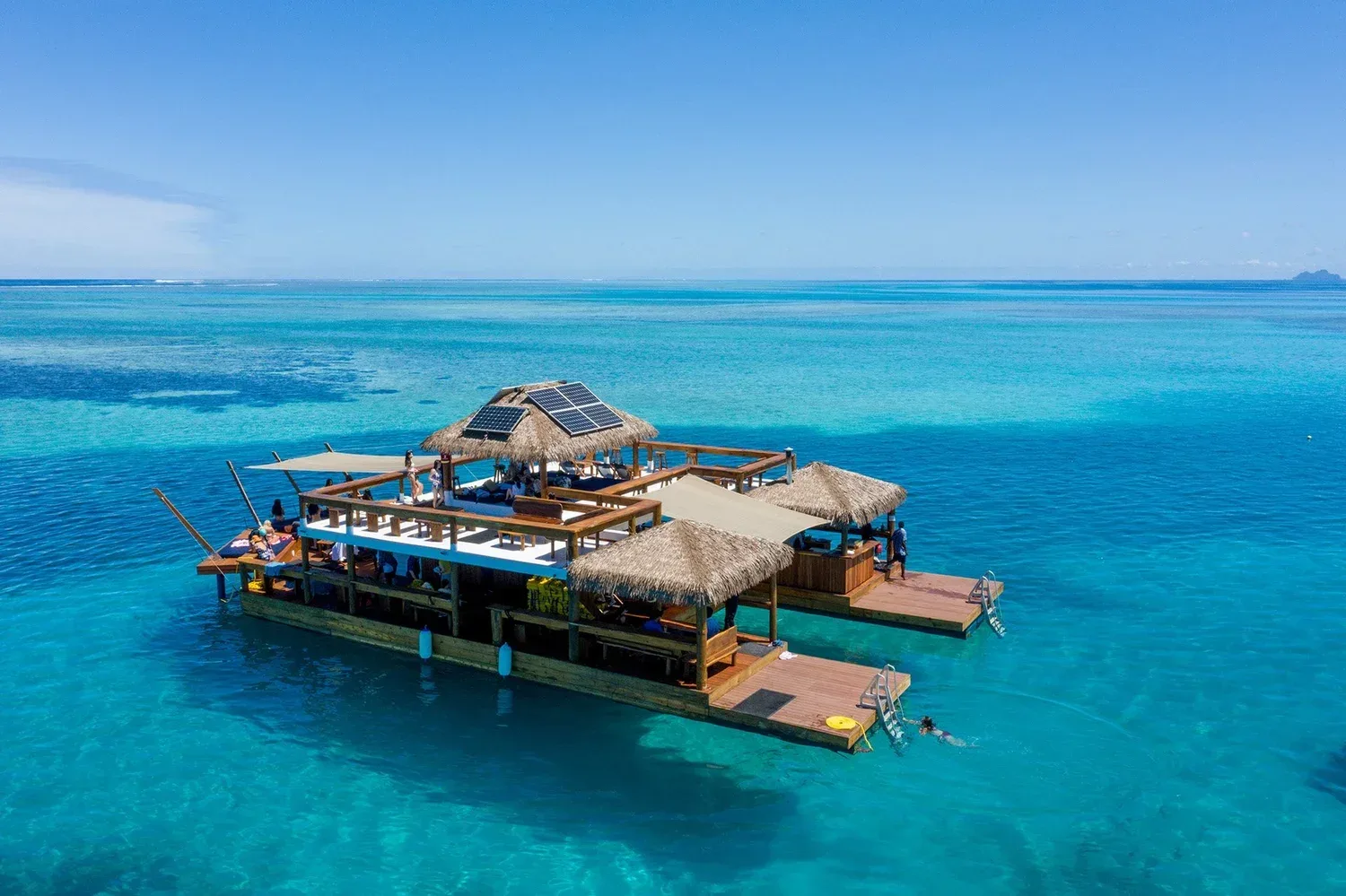 Family on floating platform surrounded by turquoise ocean