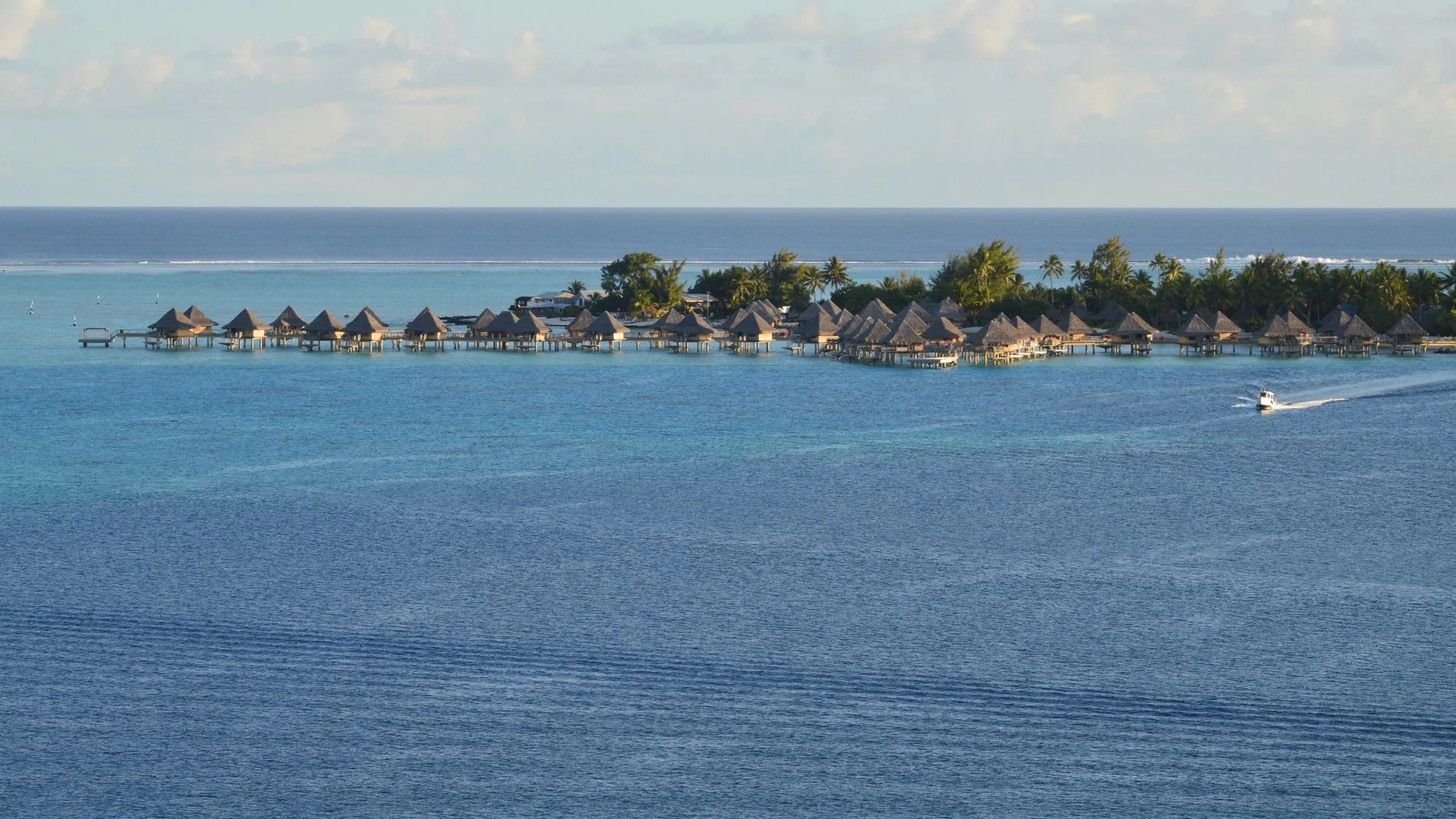Family on overwater bungalow deck with lagoon