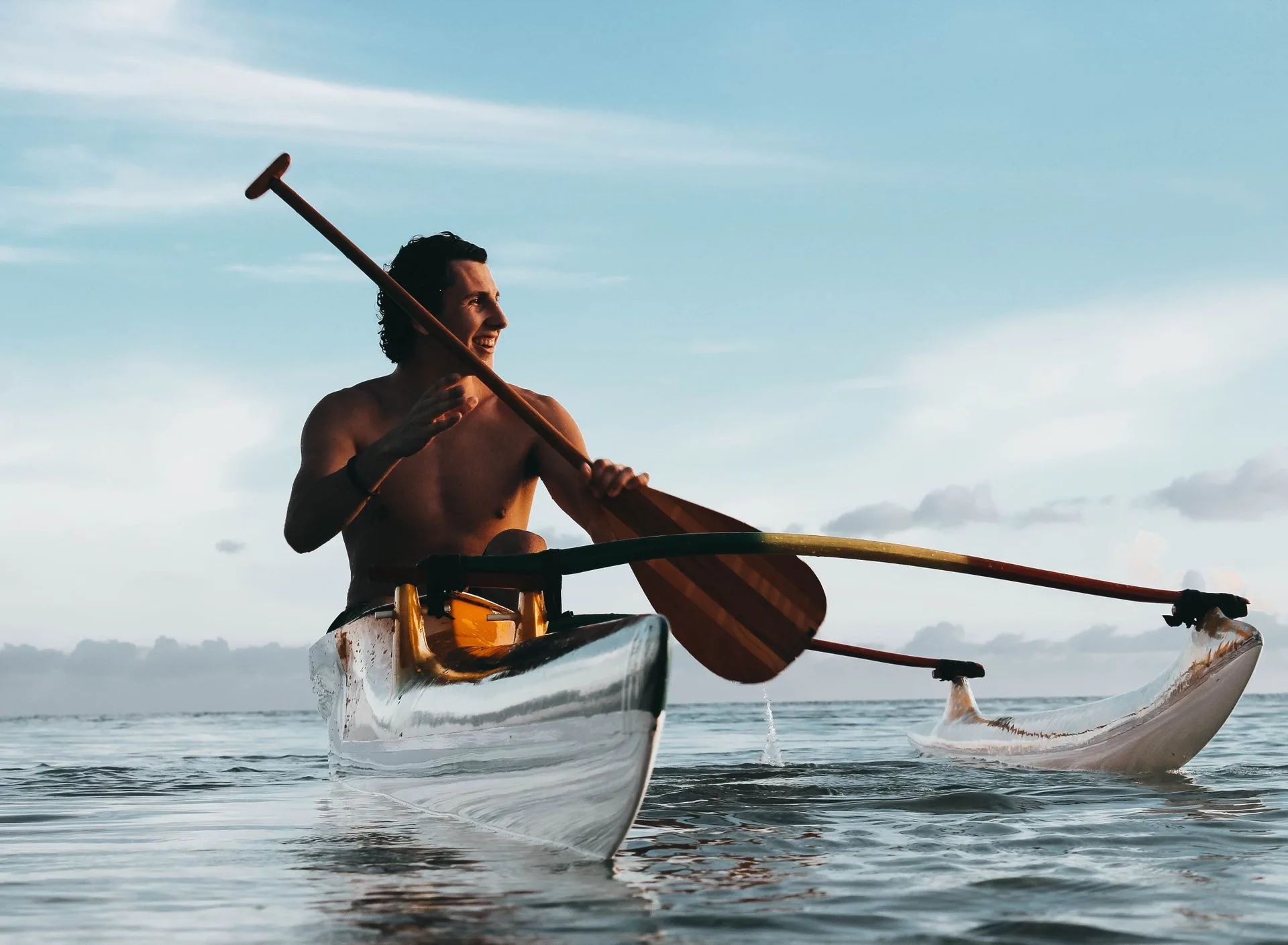 Family with traditional outrigger canoe on beach