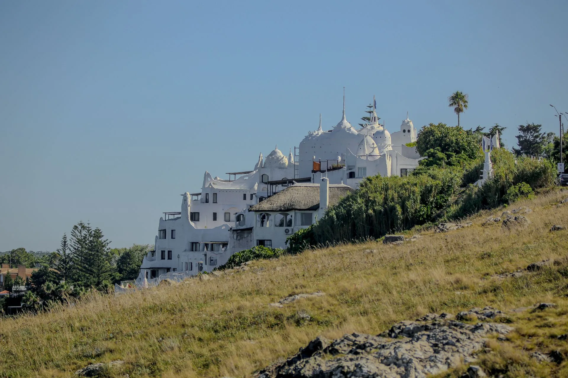 White curved architecture of Casapueblo against ocean backdrop